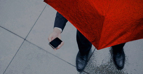 Picture of a person holding a red umbrella and smart phone